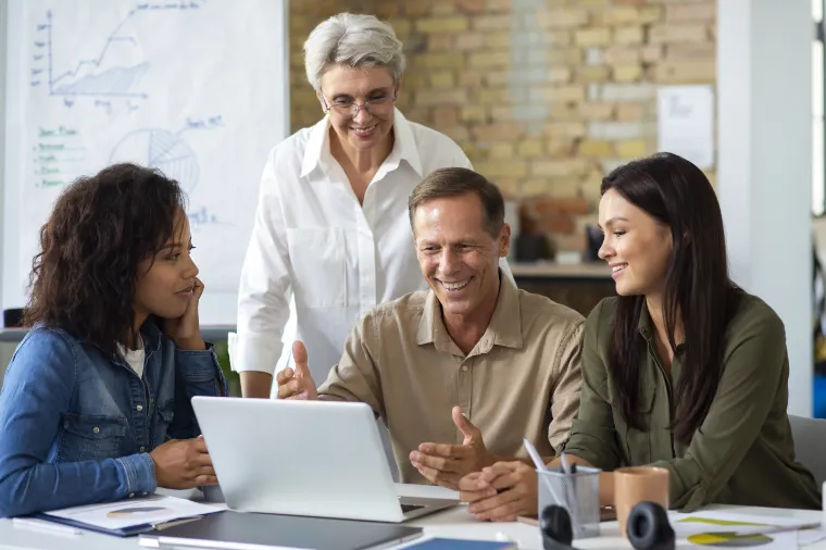 Equipe reunida em volta de um notebook analisando resultados